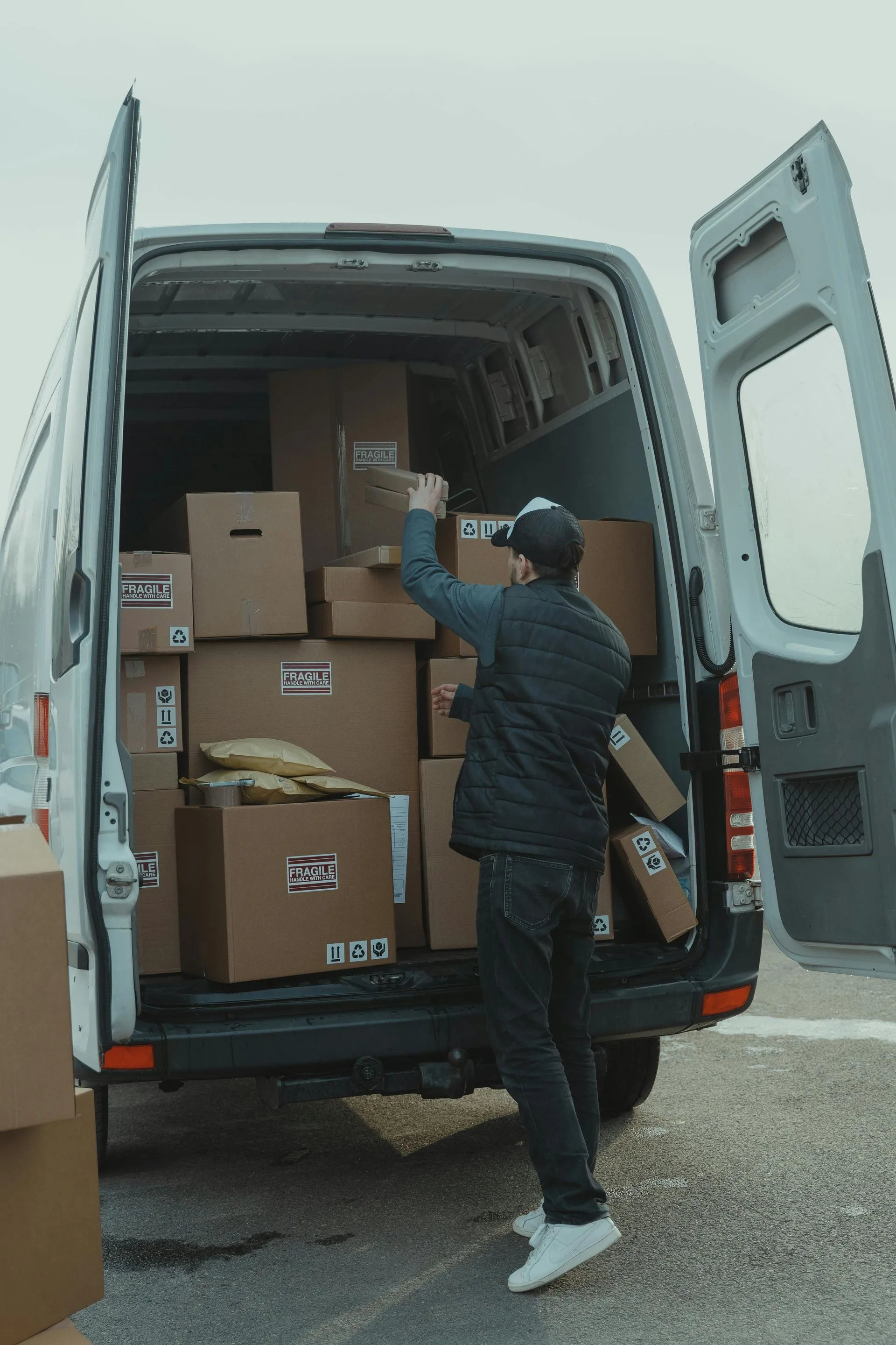 Worker loading boxes marked fragile into the back of a cargo van