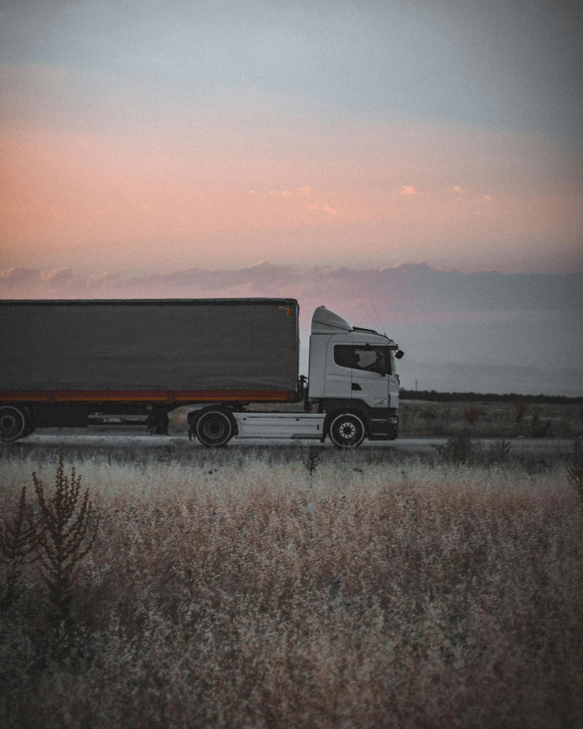 Tractor-trailer driving along a highway at sunset